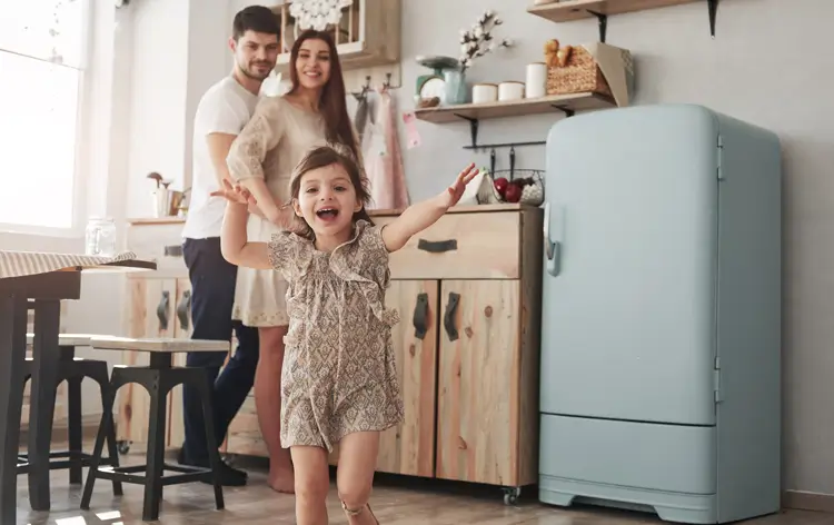 Genitori che guardano la loro figlia dopo aver chiuso la porta del frigorifero smeg